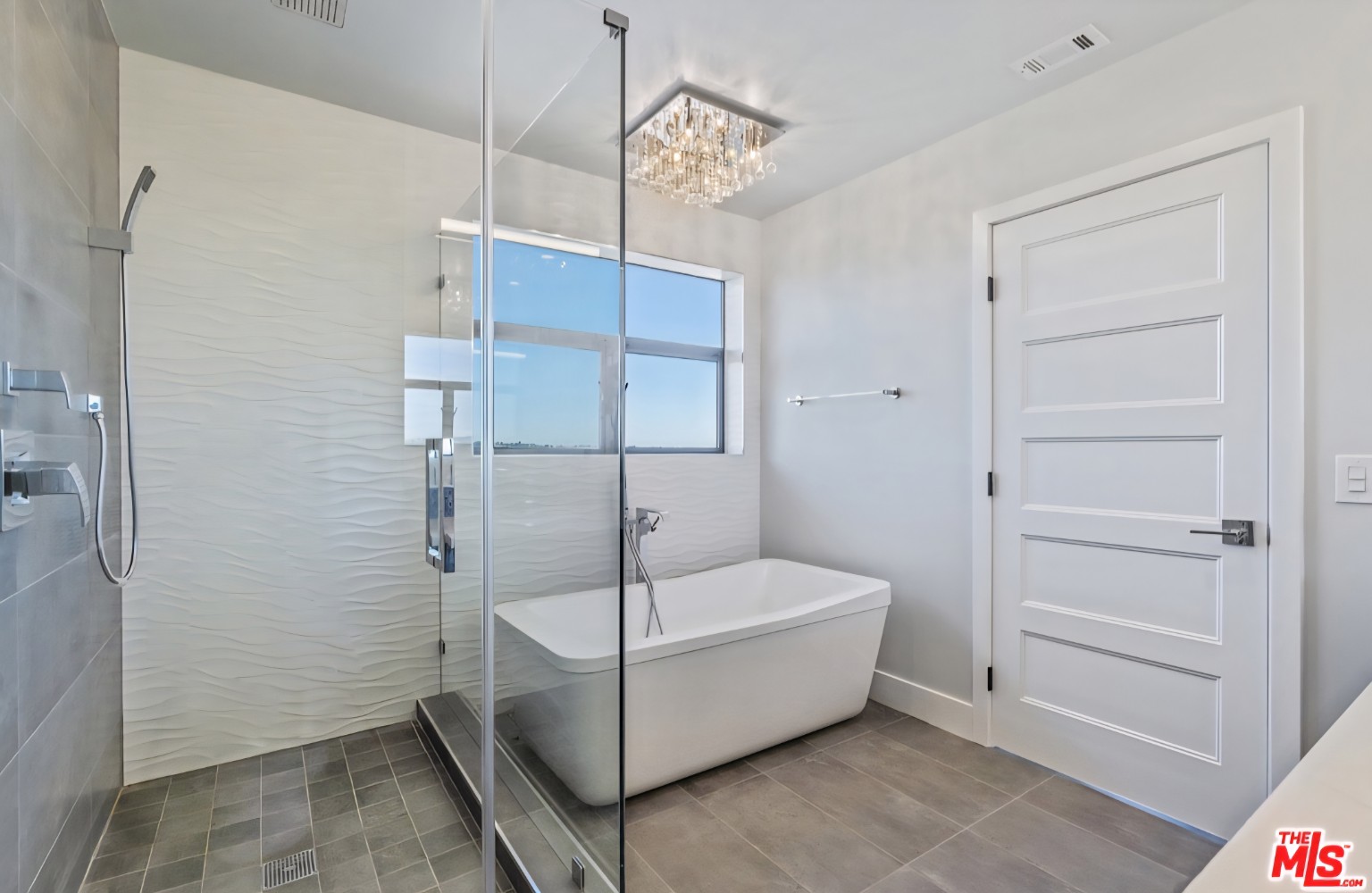 Glass shower enclosure beside a freestanding bathtub