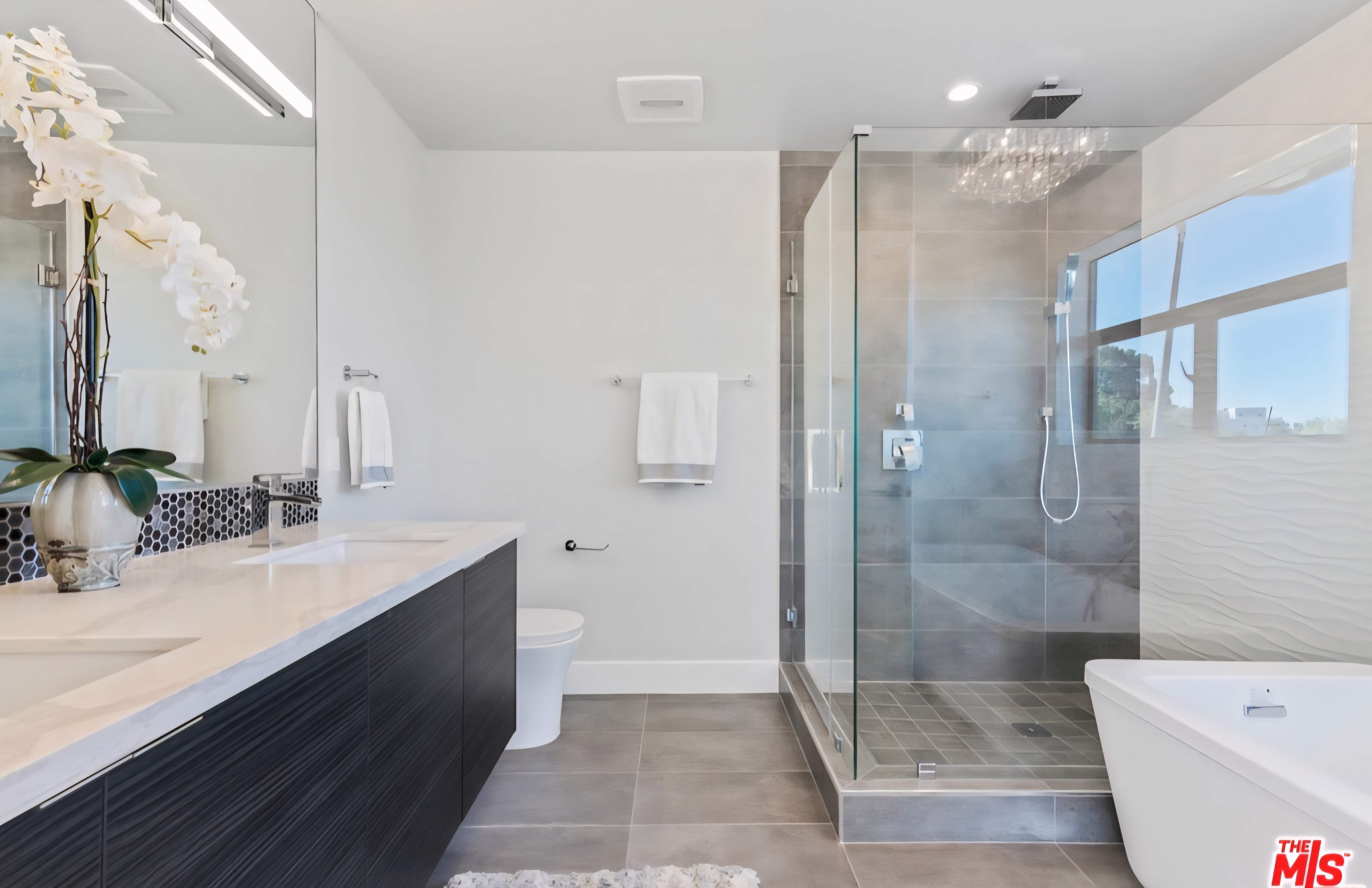 Bathroom with dark vanity, glass shower, and freestanding bathtub