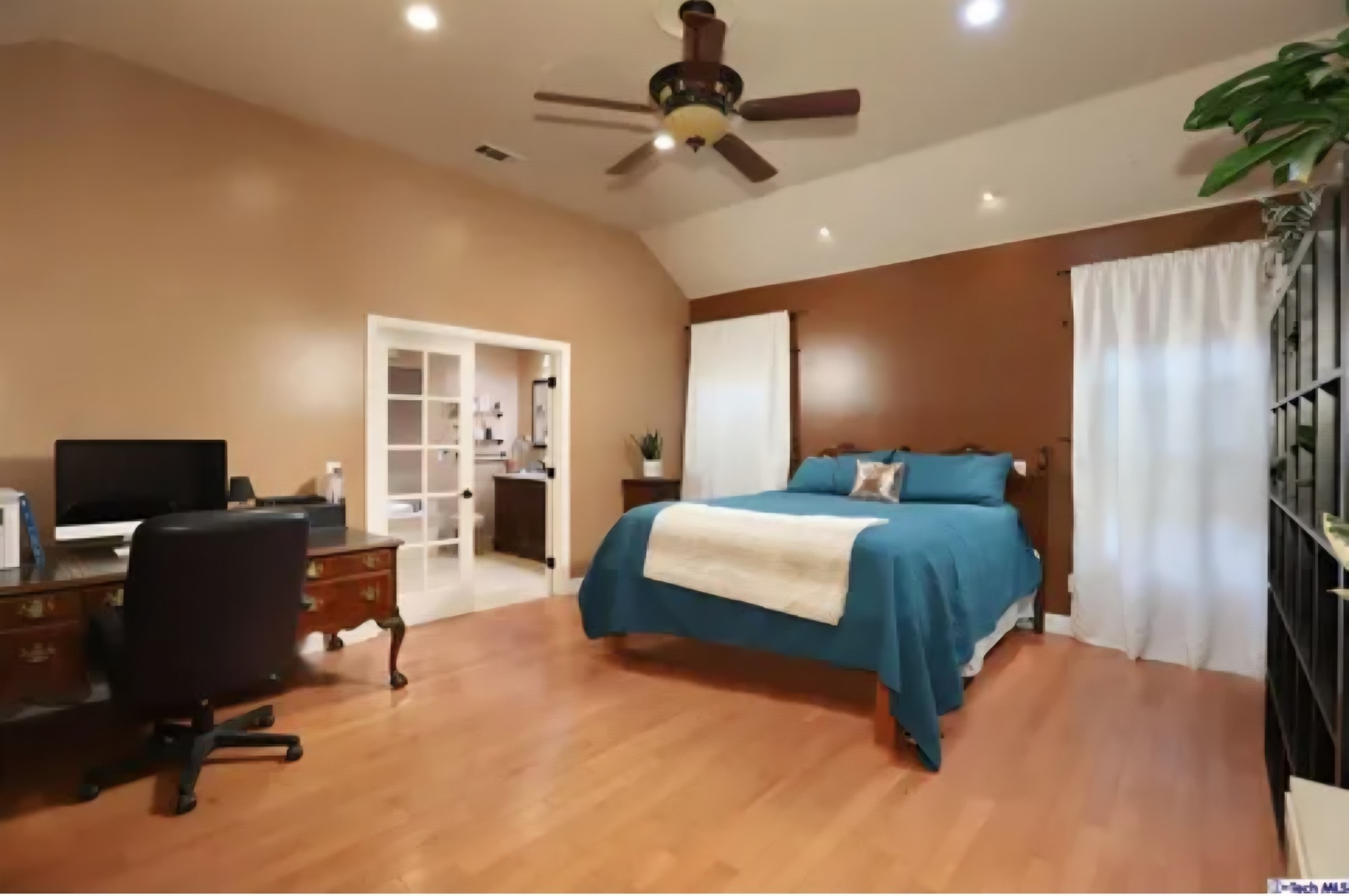 Bedroom with a vaulted ceiling, wood flooring, and adjoining bathroom