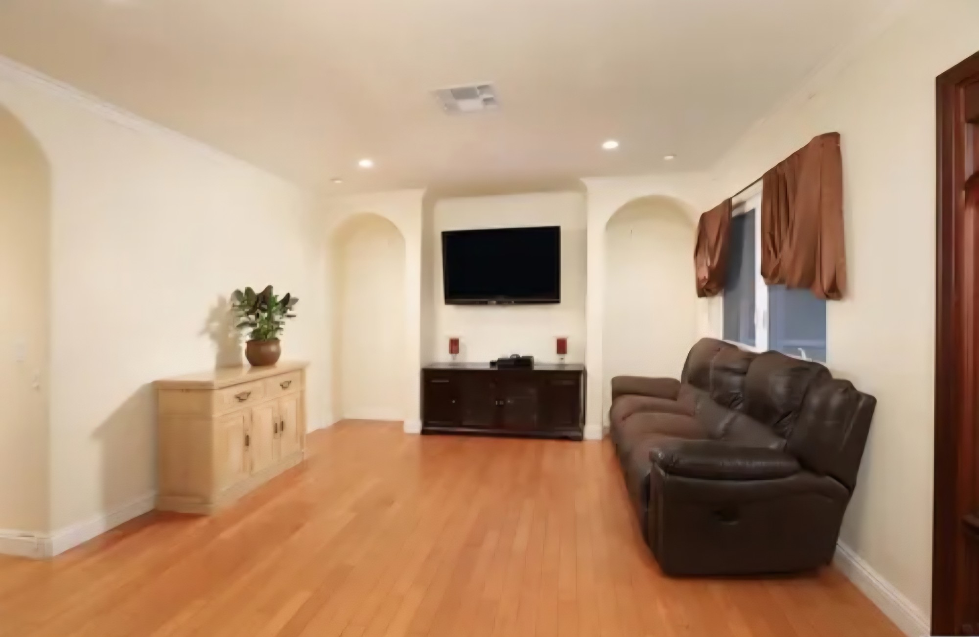 Living area with wood flooring, arched niches, and recessed lighting