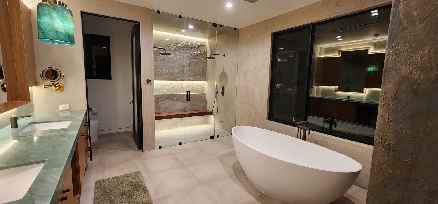 Primary bathroom with a freestanding tub, glass shower enclosure, wood vanity, and green countertop