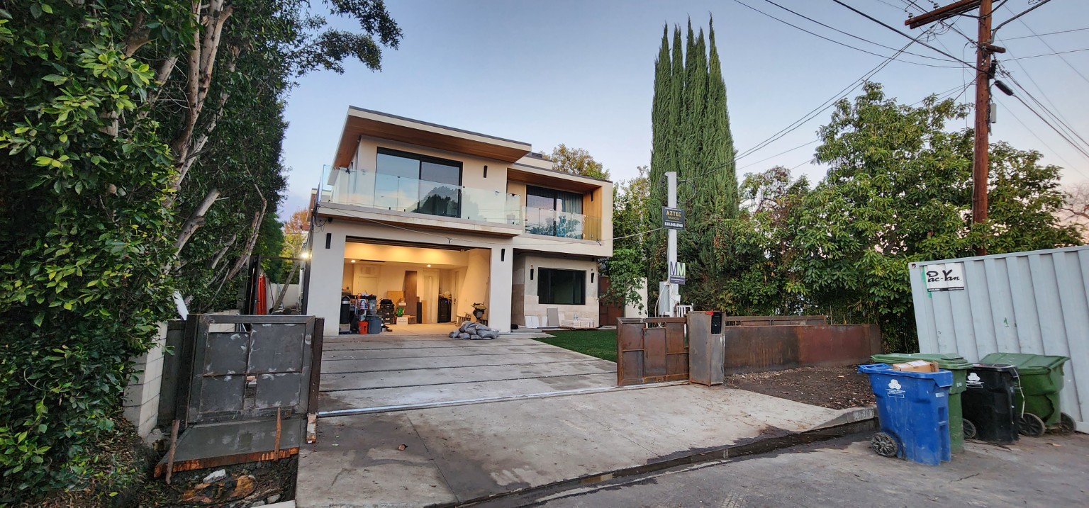 Hartsook home exterior with an upper glass balcony and construction materials in the garage