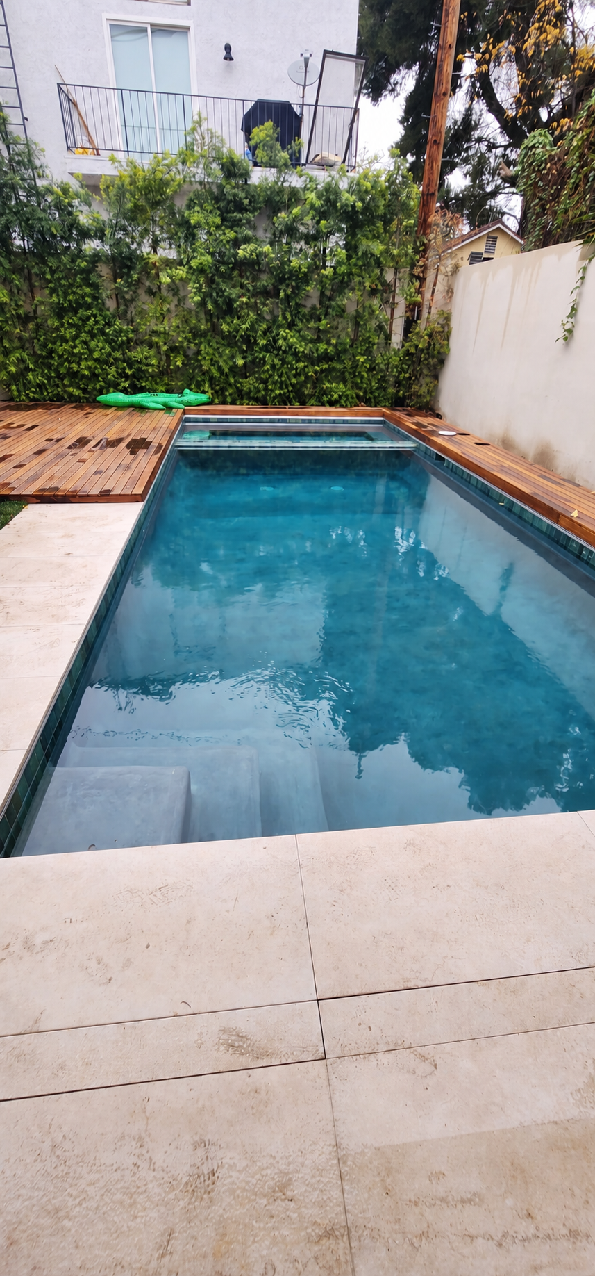 Rectangular swimming pool with stone coping and surrounding wood deck