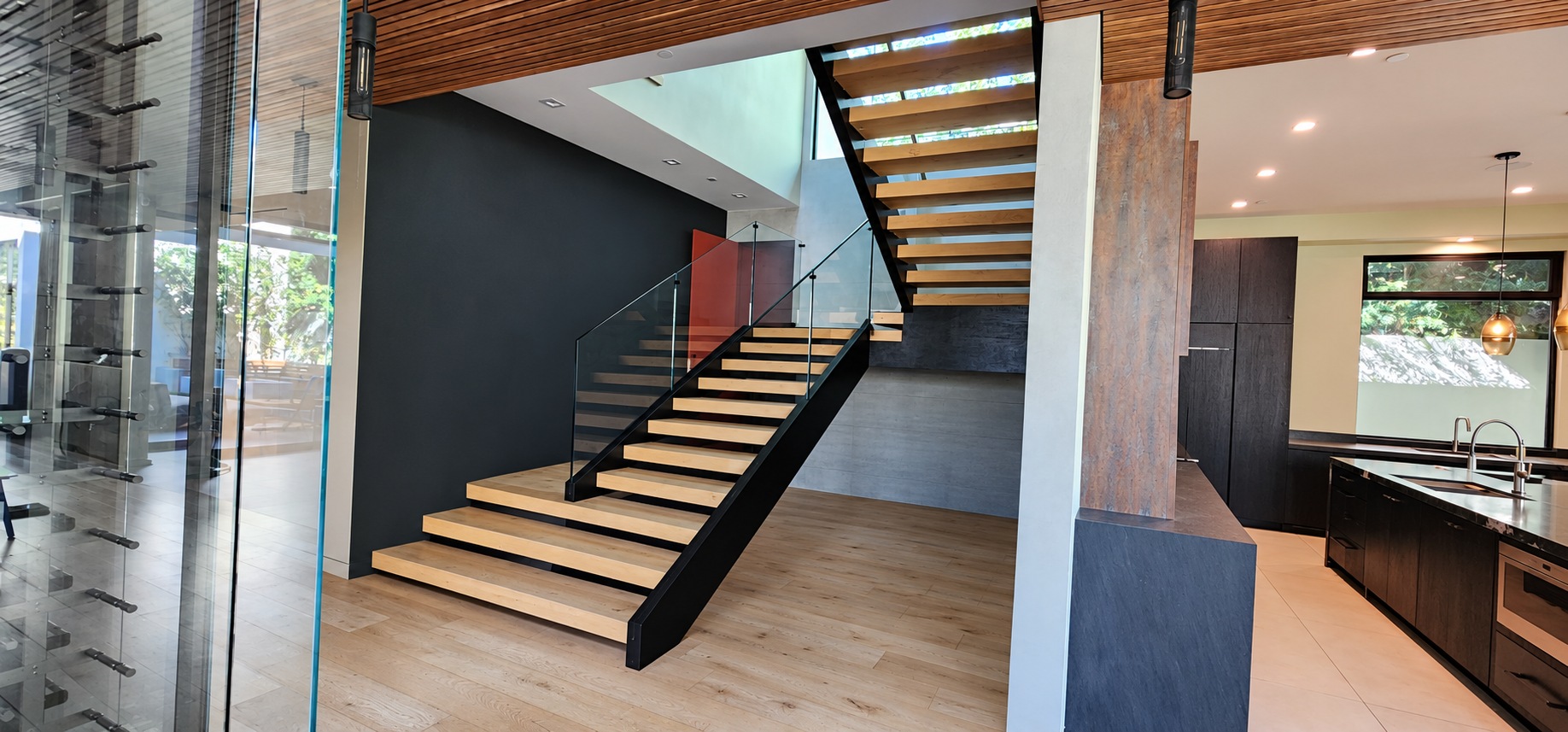 Hartsook floating wood staircase with black steel structure, glass railing, and a glass wine display
