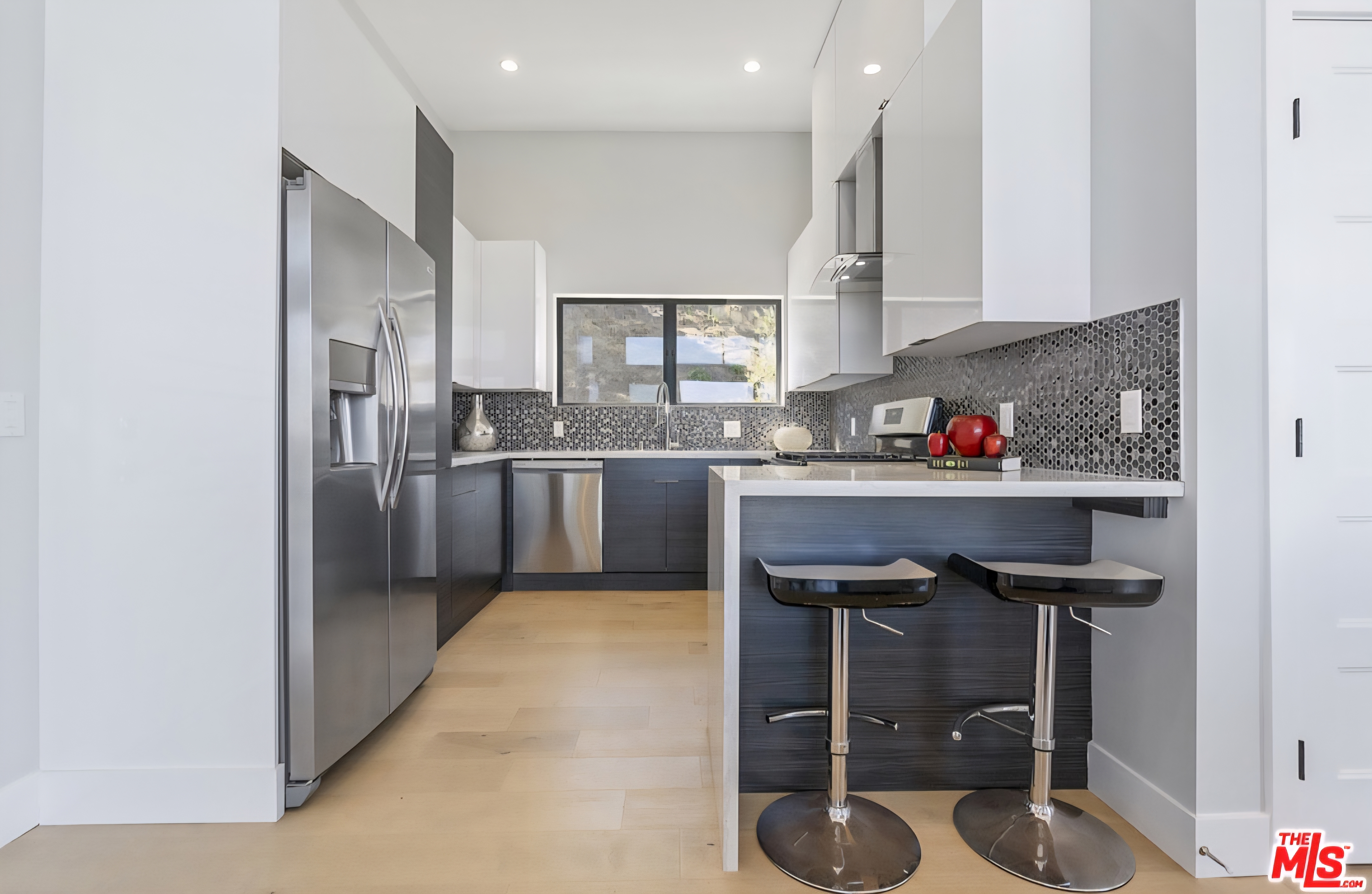 Kitchen with white upper cabinets, dark lower cabinets, and breakfast counter