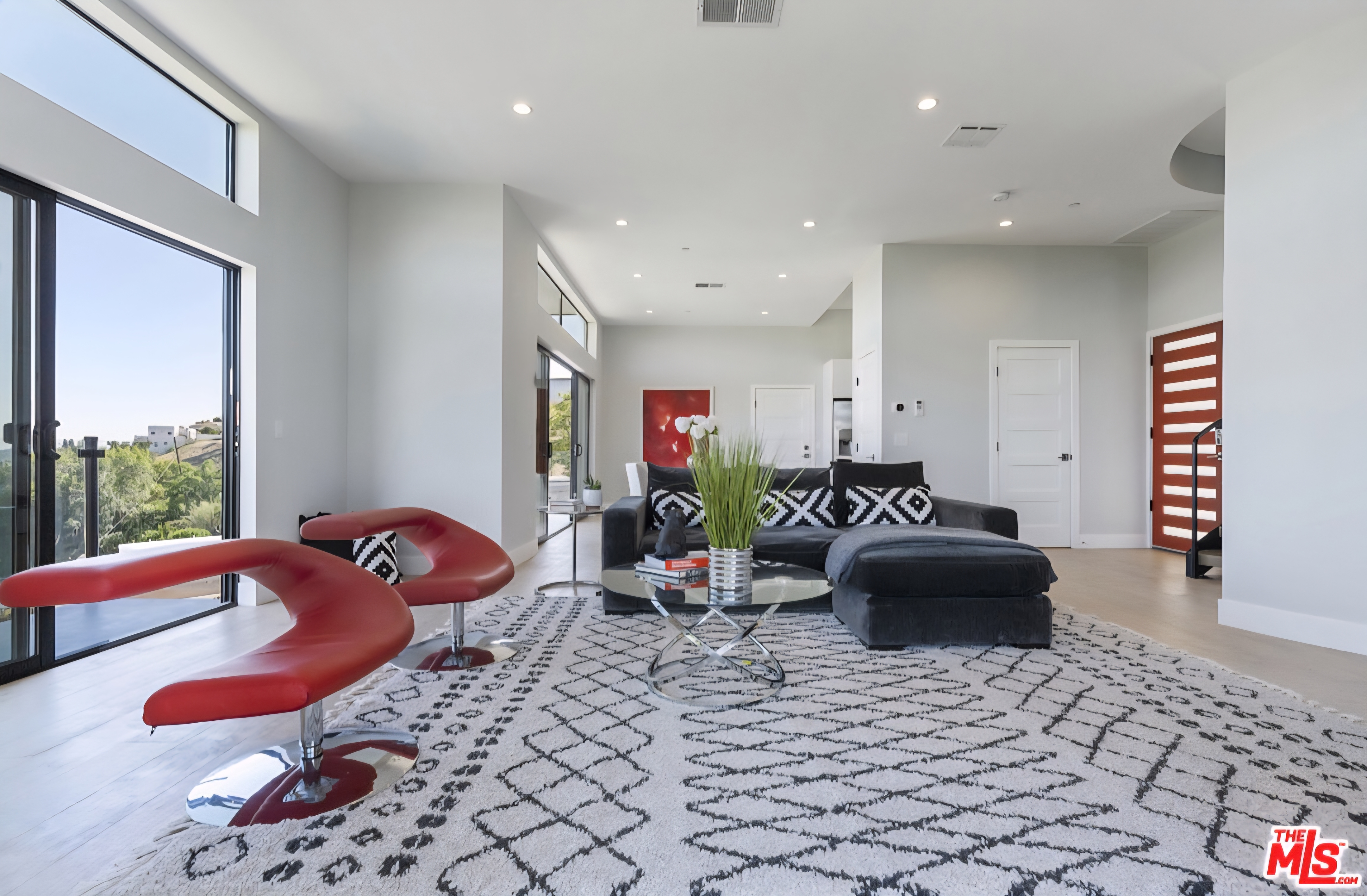 Living area with red accent chairs and large windows